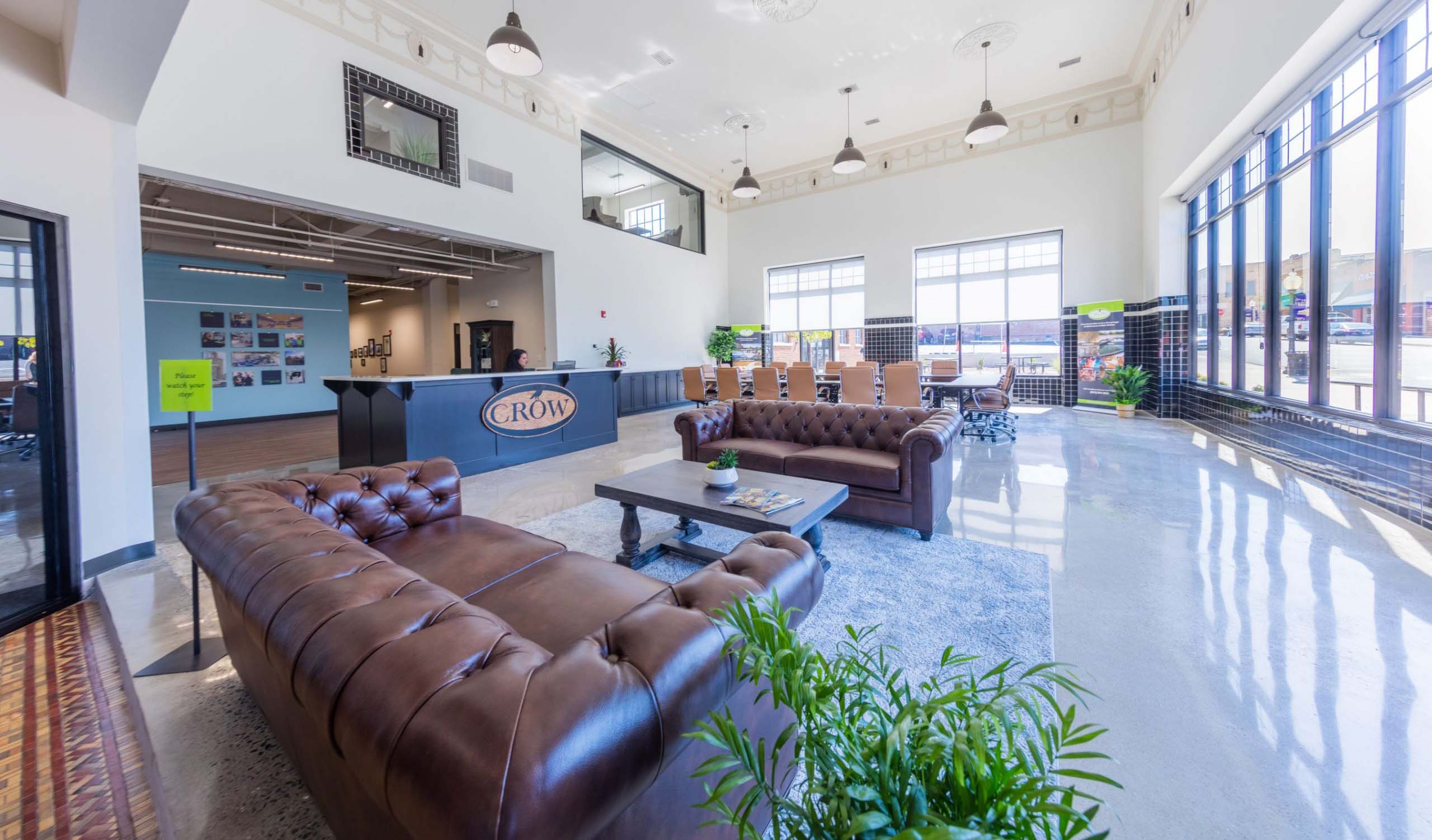 Tolm corporate headquarters lobby with high ceiling, leather couches, and walls of windows letting in lots of sunlight.
